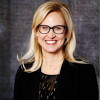 head and shoulders professional photo of blond woman wearing glasses smiling at camera