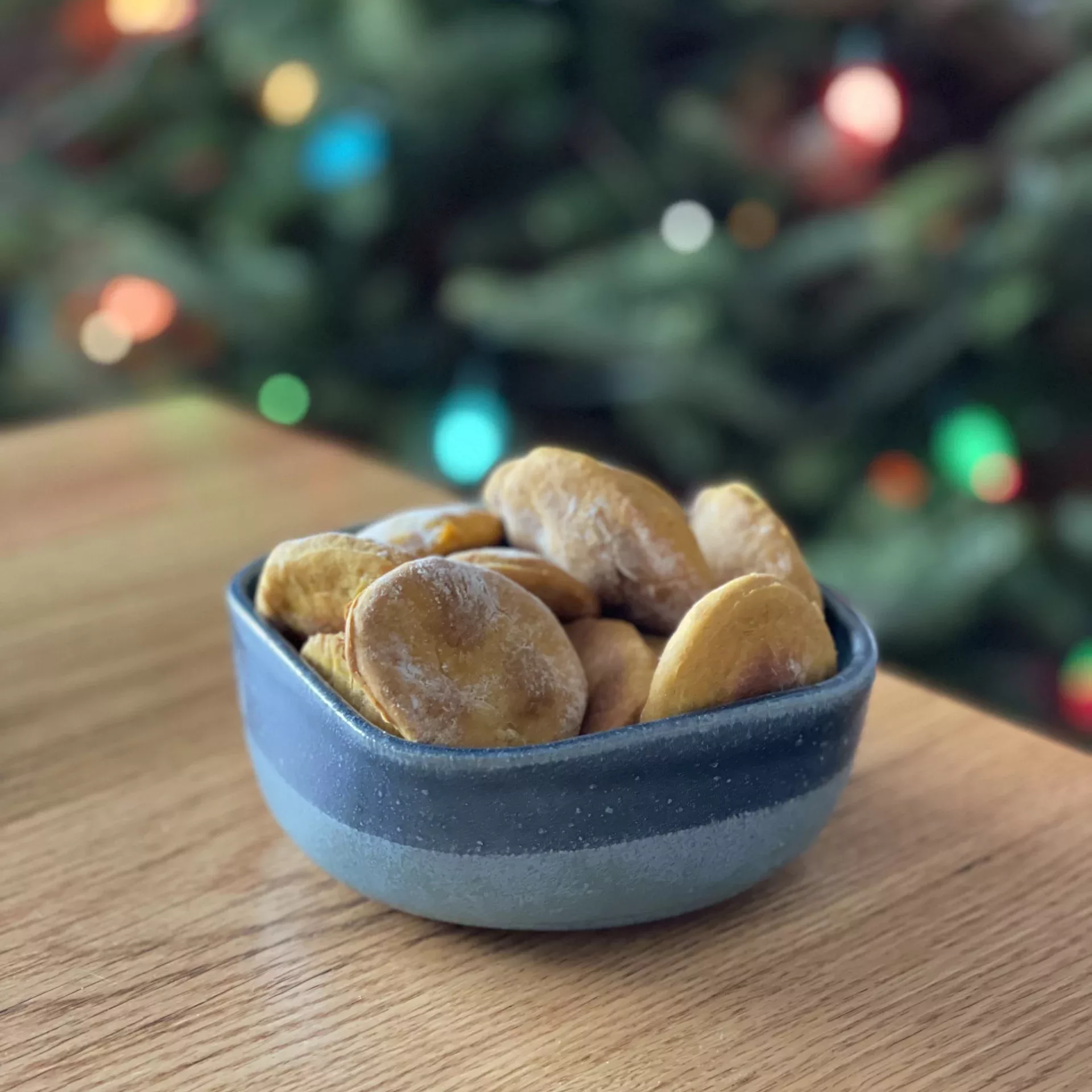 Dog treats in a bowl with holidays lights in the background